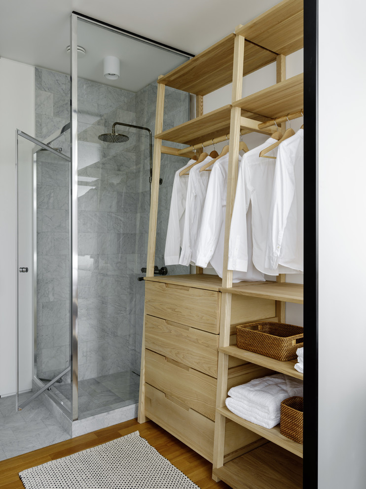 Immagine di una stanza da bagno con doccia design con doccia ad angolo, piastrelle grigie, pareti bianche, pavimento in legno massello medio, pavimento marrone e porta doccia a battente
