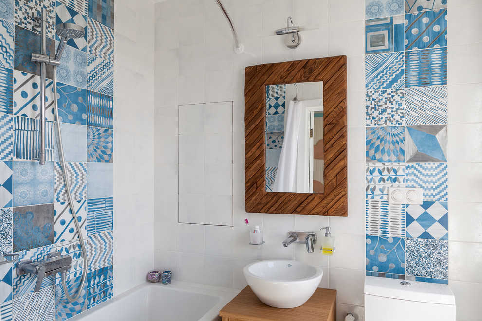 Imagen de cuarto de baño principal costero de tamaño medio con bañera encastrada sin remate, baldosas y/o azulejos azules, baldosas y/o azulejos de cerámica, encimera de madera y encimeras marrones