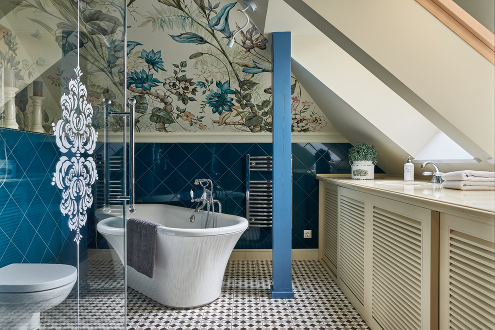 Réalisation d'une salle de bain principale tradition avec un placard à porte persienne, des portes de placard beiges, une baignoire indépendante, WC suspendus, un carrelage bleu, un mur multicolore, un lavabo encastré et un sol multicolore.