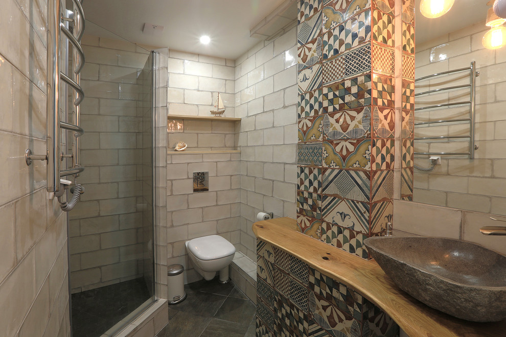 Exemple d'une petite salle de bain montagne avec WC suspendus, un carrelage blanc, des carreaux de céramique, un mur beige, un sol en carrelage de porcelaine, une vasque, un sol noir, une cabine de douche à porte battante et un plan de toilette en bois.