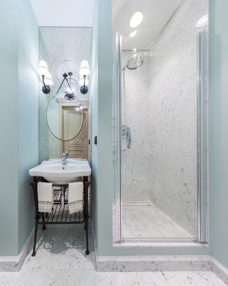 Exemple d'une salle de bain chic avec un carrelage blanc, un carrelage de pierre, un mur bleu, un sol en marbre, un plan vasque et une cabine de douche à porte battante.