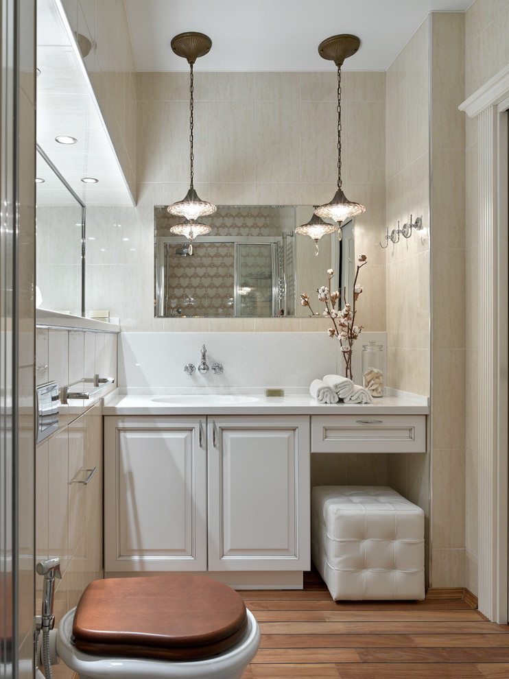 Foto på ett vintage badrum med dusch, med luckor med upphöjd panel, vita skåp, en toalettstol med separat cisternkåpa, beige kakel, ett integrerad handfat och brunt golv