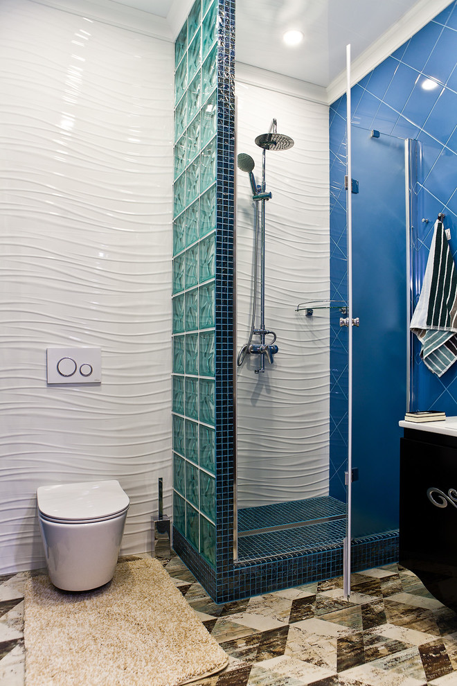 Immagine di una stanza da bagno design di medie dimensioni con ante lisce, ante nere, WC sospeso, piastrelle in ceramica, pavimento con piastrelle in ceramica, doccia alcova, piastrelle blu, piastrelle bianche e porta doccia a battente