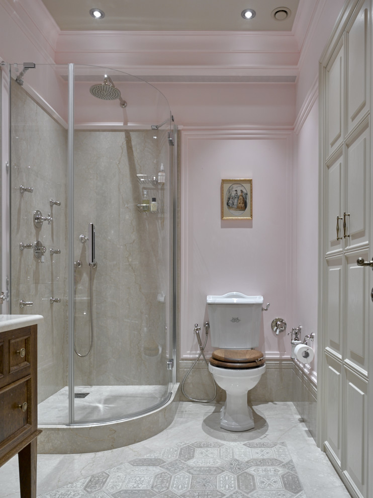 Klassisches Duschbad mit dunklen Holzschränken, Eckdusche, Wandtoilette mit Spülkasten, grauen Fliesen, rosa Wandfarbe und Falttür-Duschabtrennung in Moskau