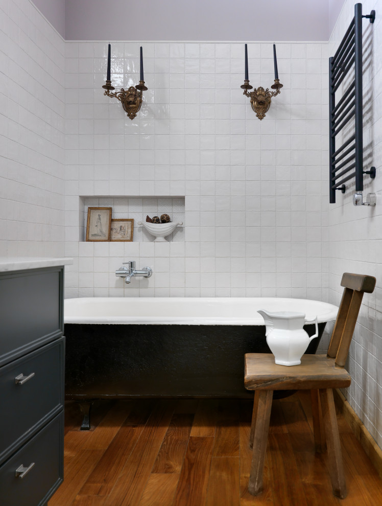 Foto di una stanza da bagno design con vasca con piedi a zampa di leone, piastrelle bianche, pareti grigie e pavimento marrone