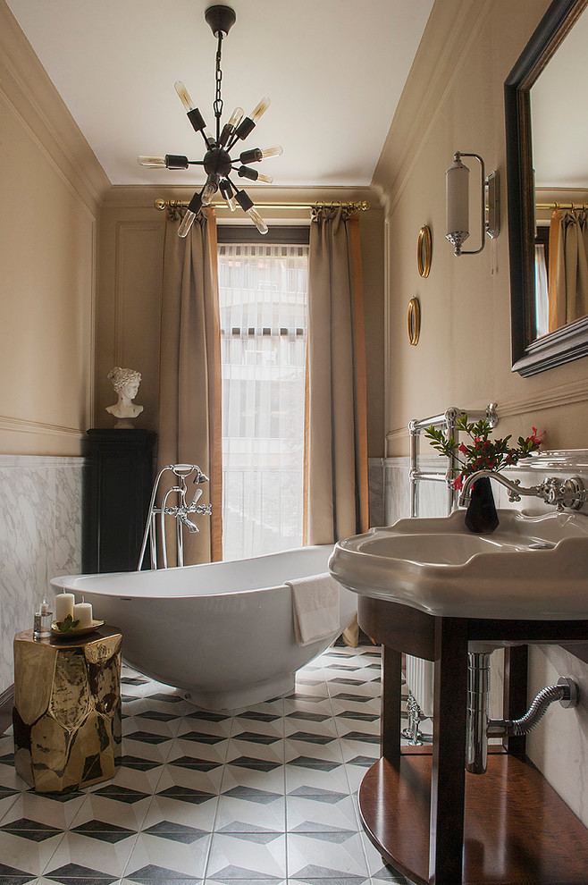 Klassisk inredning av ett en-suite badrum, med ett fristående badkar, grå kakel, beige väggar, ett konsol handfat och flerfärgat golv