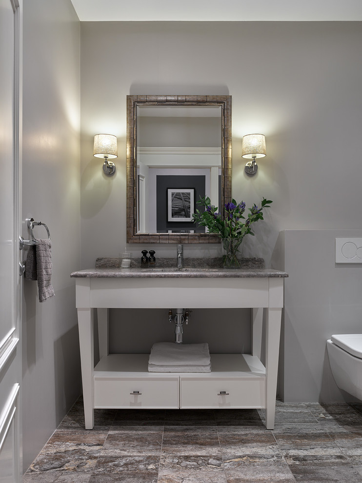 Cette photo montre une salle de bain chic avec un placard à porte plane, des portes de placard blanches, WC suspendus, un mur gris et un lavabo encastré.