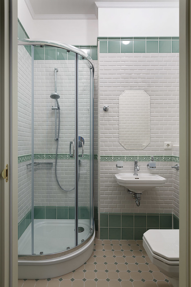 Стильный дизайн: большая ванная комната в стиле неоклассика (современная классика) с инсталляцией, керамической плиткой, полом из керамической плитки, душевой кабиной, бежевым полом, бежевой столешницей, угловым душем, белой плиткой, зеленой плиткой, белыми стенами, подвесной раковиной и душем с раздвижными дверями - последний тренд