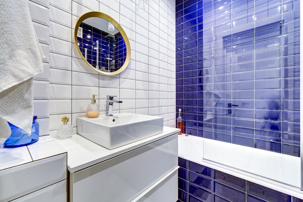 На фото: ванная комната в современном стиле с плоскими фасадами, белыми фасадами, ванной в нише, душем над ванной, синей плиткой, белой плиткой, плиткой кабанчик, белыми стенами, душевой кабиной, настольной раковиной и открытым душем