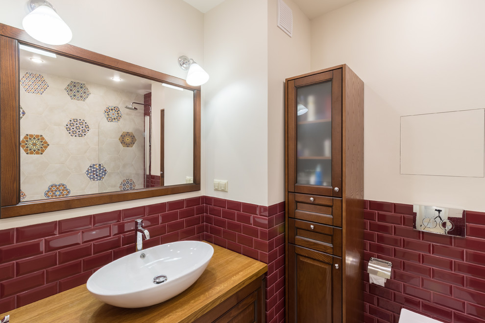 На фото: главная ванная комната в классическом стиле с фасадами с выступающей филенкой, фасадами цвета дерева среднего тона, красной плиткой, плиткой кабанчик, белыми стенами, настольной раковиной, столешницей из дерева и коричневой столешницей с
