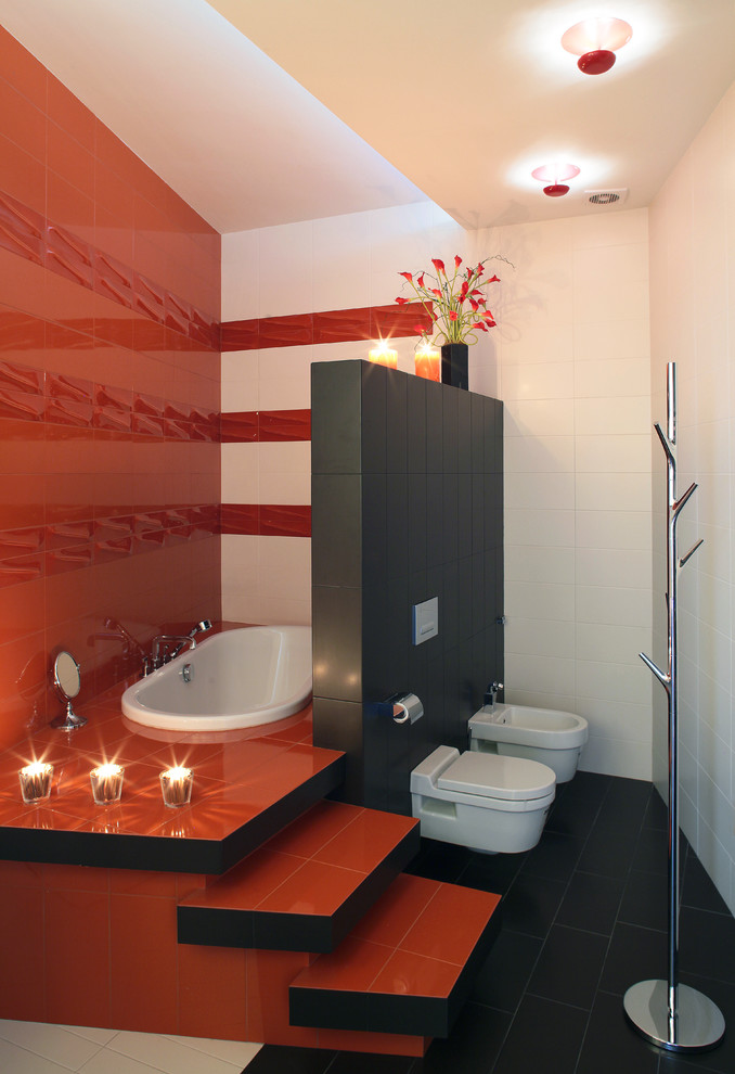 Cette photo montre une salle de bain tendance avec une baignoire posée, un bidet, un carrelage blanc, un carrelage rouge et un carrelage noir.