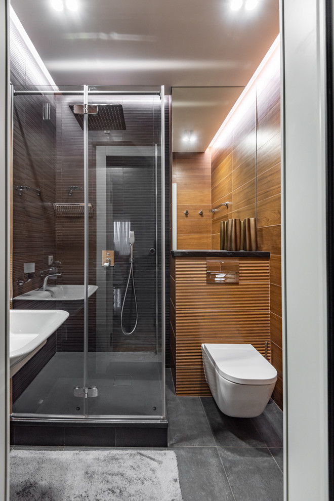 Aménagement d'une salle d'eau contemporaine avec une douche d'angle, WC suspendus, un sol gris et une cabine de douche à porte battante.