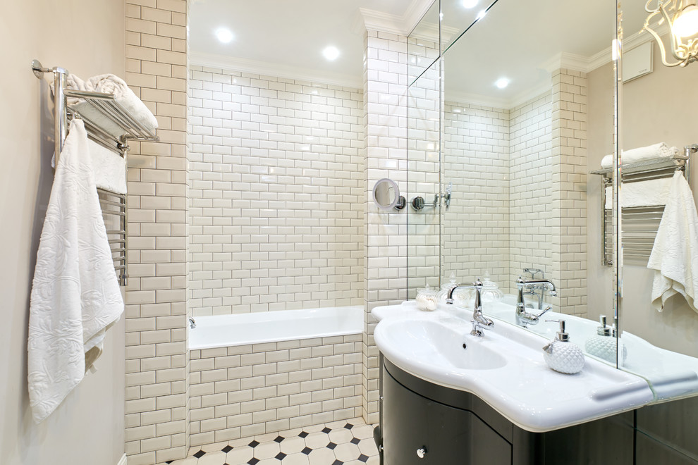 Пример оригинального дизайна: главная ванная комната среднего размера в стиле неоклассика (современная классика) с черными фасадами, ванной в нише, бежевой плиткой, керамической плиткой, полом из керамической плитки, разноцветным полом, плоскими фасадами, монолитной раковиной и белой столешницей