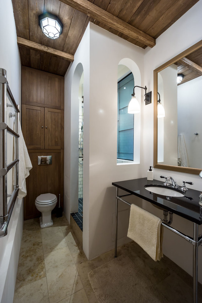 Modelo de cuarto de baño de estilo de casa de campo con sanitario de dos piezas, paredes blancas, aseo y ducha, lavabo bajoencimera y suelo beige