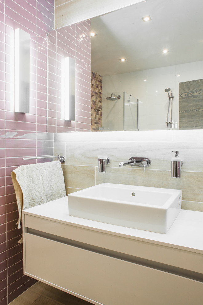 Стильный дизайн: ванная комната среднего размера в современном стиле с плоскими фасадами, белыми фасадами, угловым душем, керамической плиткой, полом из керамогранита, настольной раковиной, бежевой плиткой и розовой плиткой - последний тренд