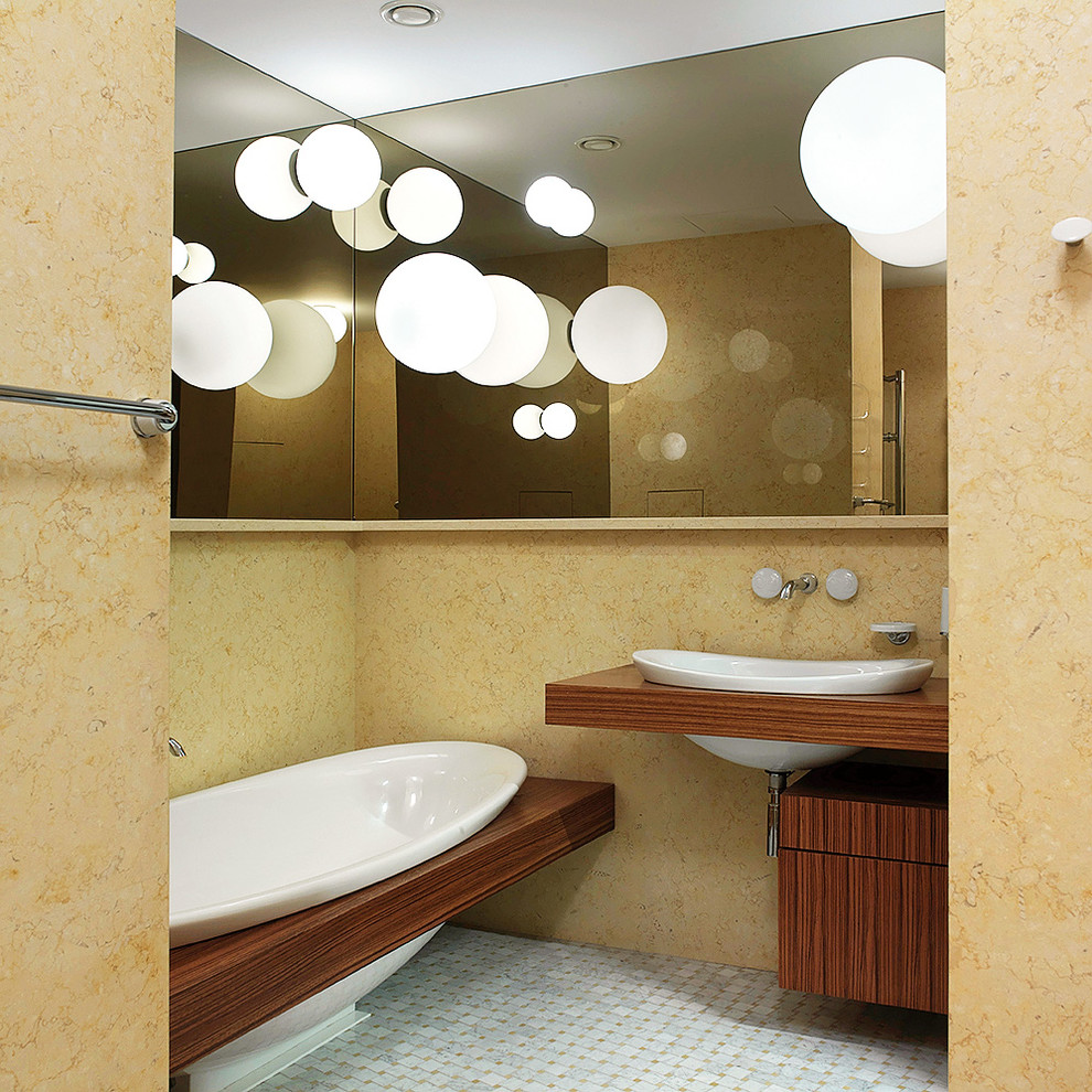 Inredning av ett modernt en-suite badrum, med släta luckor, skåp i mellenmörkt trä, ett platsbyggt badkar, beige kakel, marmorgolv, ett nedsänkt handfat och grått golv
