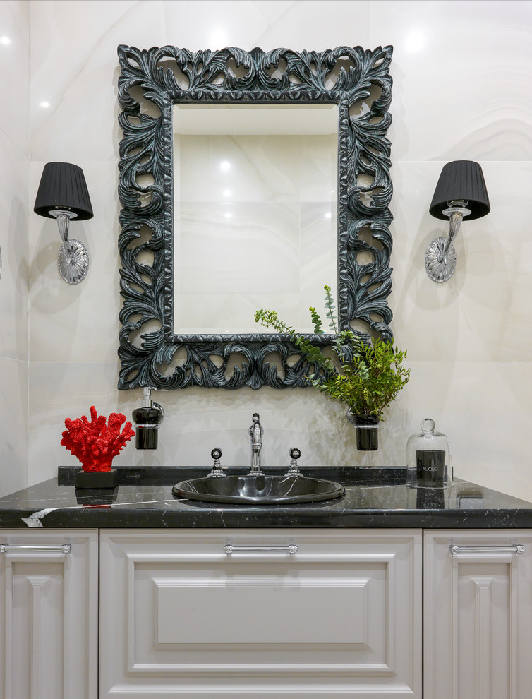 Klassisches Badezimmer mit profilierten Schrankfronten, weißen Schränken, beigen Fliesen, Einbauwaschbecken und schwarzer Waschtischplatte in Moskau