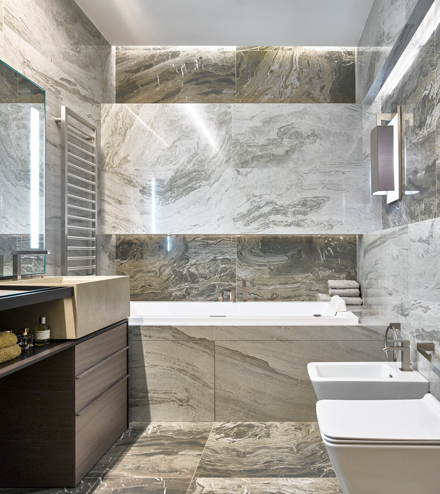 На фото: главная ванная комната в современном стиле с биде, бежевой плиткой, монолитной раковиной, бежевым полом и полновстраиваемой ванной