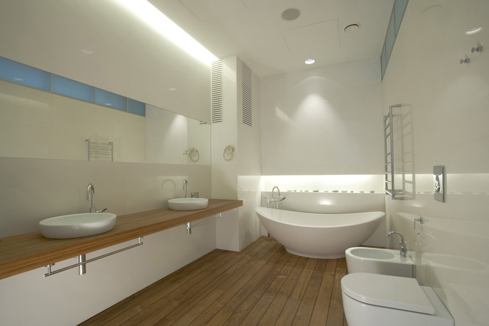 Design ideas for a medium sized contemporary ensuite bathroom in Saint Petersburg with flat-panel cabinets, white cabinets, a freestanding bath, an alcove shower, a wall mounted toilet, white tiles, stone slabs, white walls, medium hardwood flooring, a built-in sink and wooden worktops.