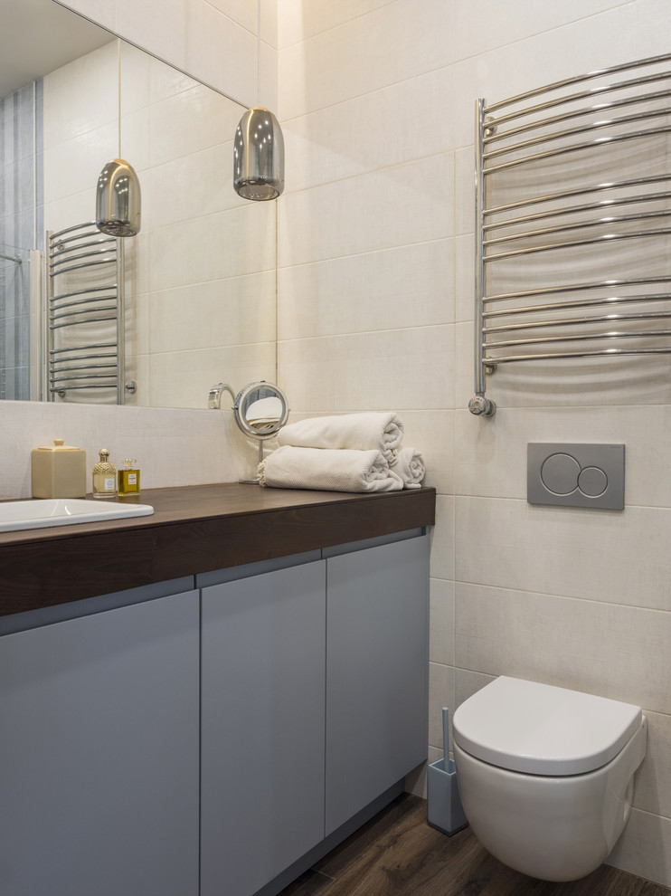 На фото: ванная комната среднего размера в современном стиле с серыми фасадами, инсталляцией, бежевой плиткой, керамической плиткой, деревянным полом, столешницей из дерева, коричневым полом, коричневой столешницей и накладной раковиной