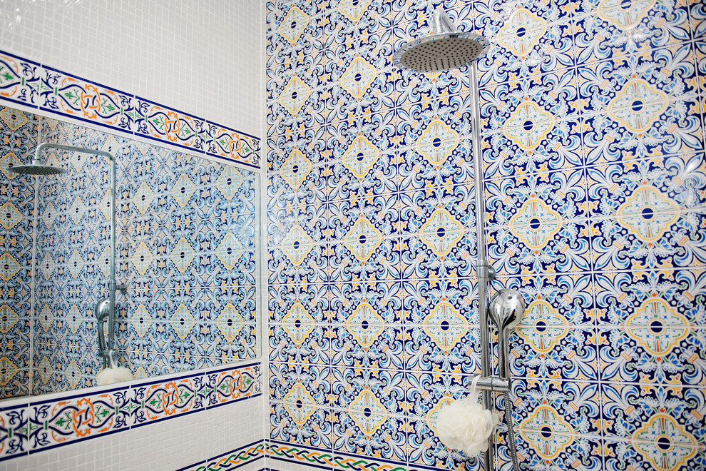 Bild på ett mellanstort funkis vit vitt en-suite badrum, med öppna hyllor, en jacuzzi, en dusch/badkar-kombination, en vägghängd toalettstol, flerfärgad kakel, keramikplattor, vita väggar, klinkergolv i keramik, ett fristående handfat, kaklad bänkskiva, blått golv och dusch med duschdraperi