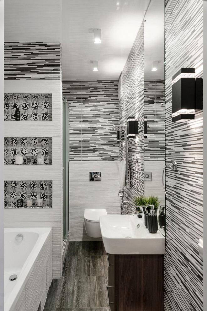 Пример оригинального дизайна: ванная комната в современном стиле с плоскими фасадами, темными деревянными фасадами, ванной в нише, инсталляцией, черно-белой плиткой, разноцветными стенами, душевой кабиной, подвесной раковиной и серым полом