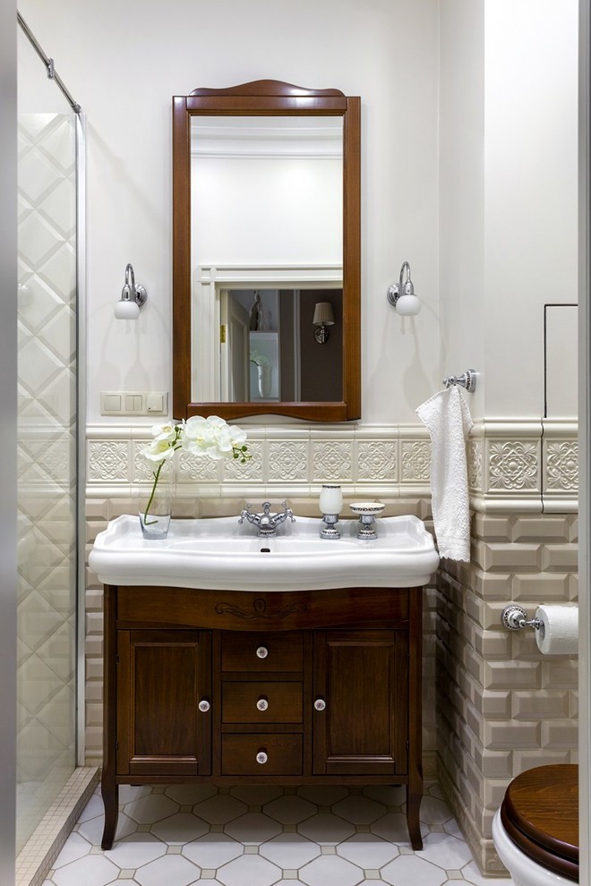 На фото: ванная комната в стиле неоклассика (современная классика) с фасадами в стиле шейкер, темными деревянными фасадами, душем в нише, бежевой плиткой, плиткой кабанчик, белыми стенами, душевой кабиной, накладной раковиной и белым полом
