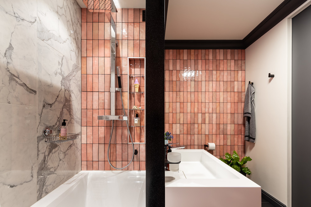 Idéer för badrum, med släta luckor, skåp i mellenmörkt trä, ett undermonterat badkar, en vägghängd toalettstol, rosa kakel, keramikplattor, rosa väggar, klinkergolv i porslin, ett väggmonterat handfat och svart golv
