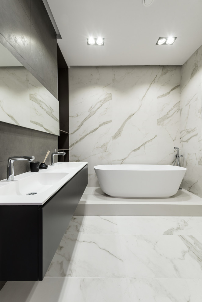 Стильный дизайн: главная ванная комната в современном стиле с плоскими фасадами, черными фасадами, отдельно стоящей ванной и раковиной с несколькими смесителями - последний тренд