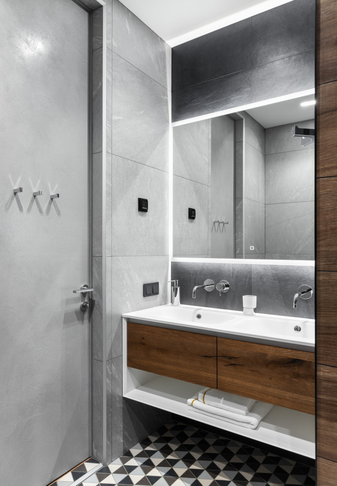 Inspiration for a medium sized contemporary family bathroom in Moscow with flat-panel cabinets, medium wood cabinets, an alcove bath, an alcove shower, a wall mounted toilet, black tiles, porcelain tiles, grey walls, porcelain flooring, a vessel sink, solid surface worktops, multi-coloured floors, a shower curtain, white worktops, an enclosed toilet, double sinks and a floating vanity unit.