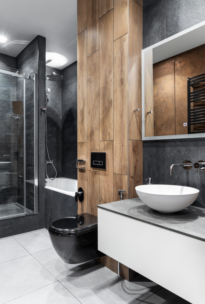 Inspiration för mellanstora moderna grått en-suite badrum, med släta luckor, grå skåp, ett badkar i en alkov, en dusch i en alkov, en vägghängd toalettstol, grå kakel, porslinskakel, svarta väggar, klinkergolv i porslin, ett fristående handfat, bänkskiva i akrylsten, grått golv och dusch med duschdraperi