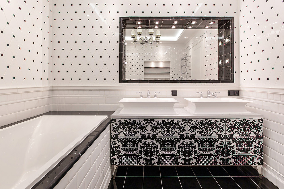 Cette photo montre une salle de bain chic avec un placard à porte plane, une baignoire en alcôve, un carrelage blanc, un carrelage noir et blanc, un carrelage noir, une vasque et un sol noir.