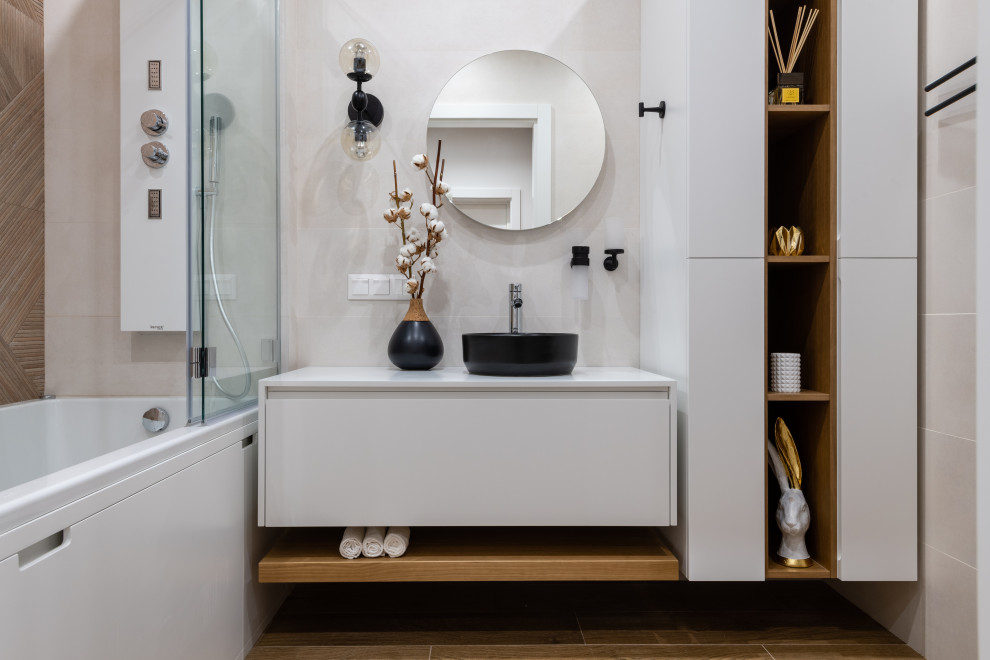На фото: главная ванная комната в современном стиле с плоскими фасадами, белыми фасадами, ванной в нише, душем над ванной, бежевой плиткой, настольной раковиной, белой столешницей, тумбой под одну раковину и подвесной тумбой