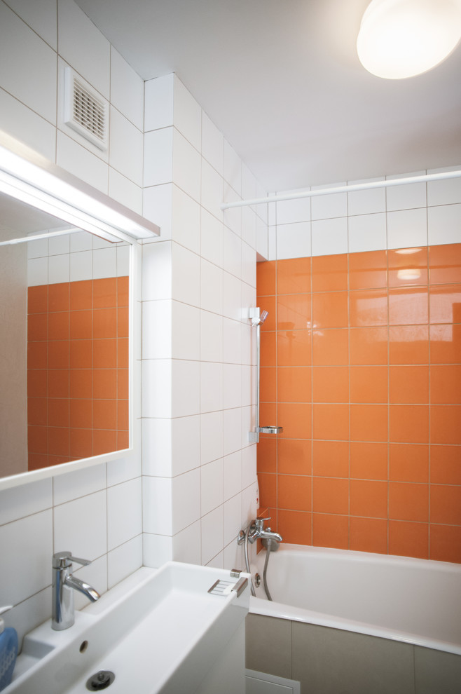 Esempio di una piccola stanza da bagno padronale nordica con ante lisce, ante bianche, vasca ad alcova, vasca/doccia, WC sospeso, piastrelle in ceramica, pareti bianche, pavimento in gres porcellanato e piastrelle arancioni