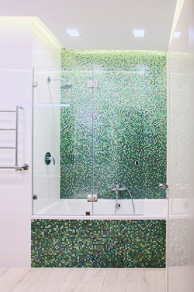 Foto de cuarto de baño actual con bañera empotrada, combinación de ducha y bañera, baldosas y/o azulejos verdes, baldosas y/o azulejos en mosaico, paredes blancas y suelo de madera clara