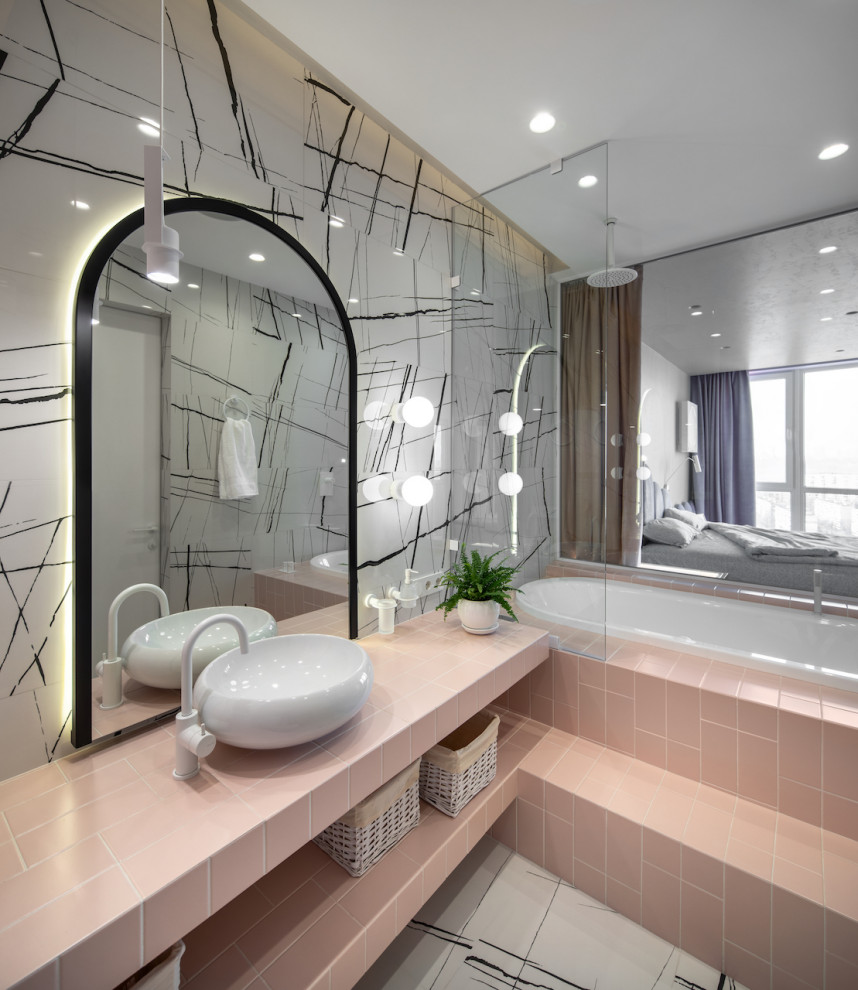 Foto på ett mellanstort rosa en-suite badrum, med öppna hyllor, ett undermonterat badkar, en dusch/badkar-kombination, en vägghängd toalettstol, svart och vit kakel, porslinskakel, vita väggar, klinkergolv i porslin, ett fristående handfat, kaklad bänkskiva, vitt golv och med dusch som är öppen