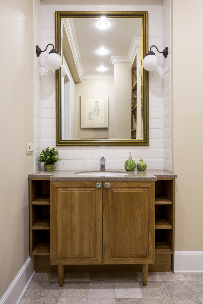 Cette photo montre une salle de bain chic en bois brun avec un placard avec porte à panneau surélevé, un carrelage blanc, un carrelage métro, un mur beige, un lavabo encastré et un sol gris.