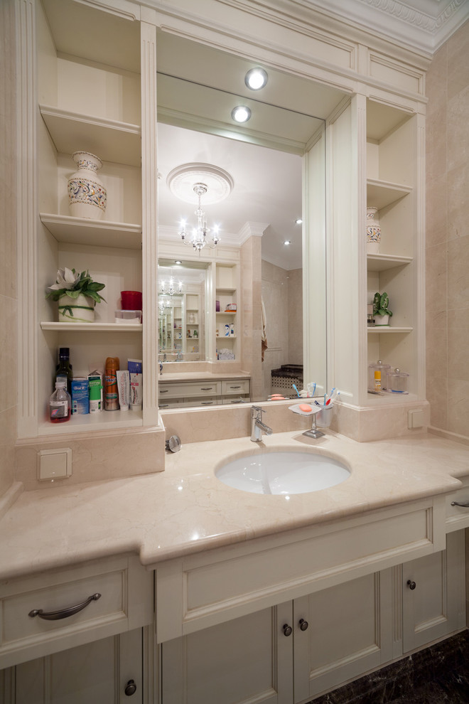 Пример оригинального дизайна: большая главная ванная комната в классическом стиле с фасадами с утопленной филенкой, бежевыми фасадами, полновстраиваемой ванной, бежевой плиткой, мраморной плиткой, мраморным полом, врезной раковиной и мраморной столешницей