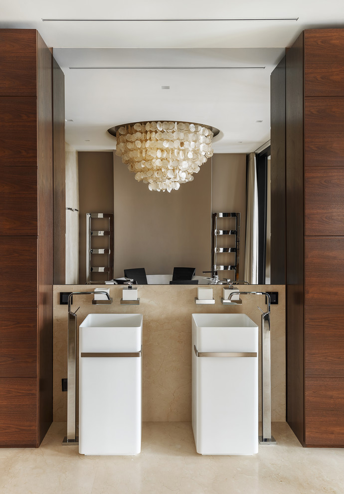 Bild på ett funkis en-suite badrum, med ett fristående badkar, ett piedestal handfat, beiget golv, släta luckor, skåp i mellenmörkt trä, beige kakel, marmorkakel och beige väggar