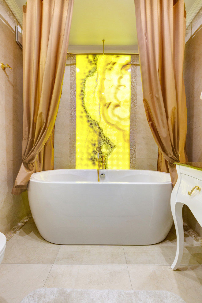 Источник вдохновения для домашнего уюта: главная ванная комната среднего размера в стиле неоклассика (современная классика) с отдельно стоящей ванной, инсталляцией, бежевой плиткой, плиткой из листового камня, бежевыми стенами, полом из керамической плитки, стеклянной столешницей, бежевым полом, тумбой под одну раковину, напольной тумбой и панелями на стенах