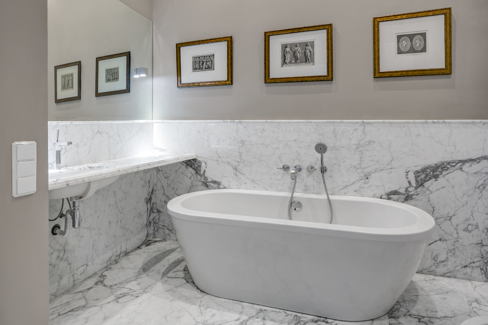 На фото: ванная комната в стиле неоклассика (современная классика) с отдельно стоящей ванной, мраморным полом, врезной раковиной и серыми стенами с