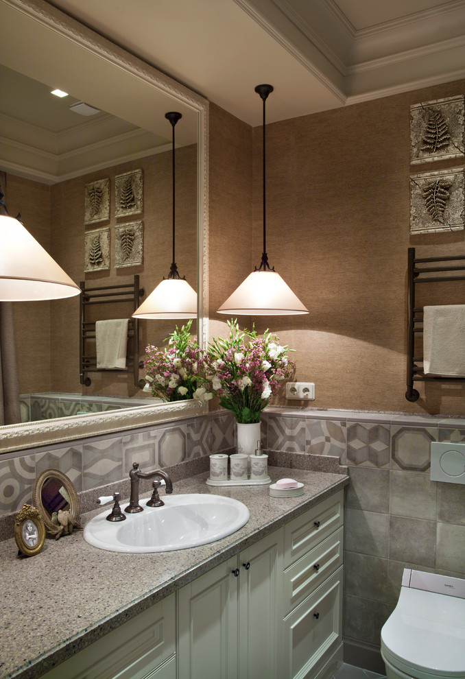 Modern inredning av ett badrum, med luckor med infälld panel, vita skåp, bruna väggar, ett nedsänkt handfat, en toalettstol med hel cisternkåpa och grå kakel