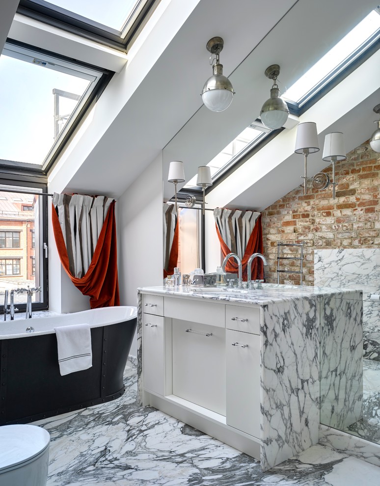 Réalisation d'une salle de bain design avec un placard à porte plane, des portes de placard blanches, une baignoire indépendante, un mur blanc et un sol en marbre.