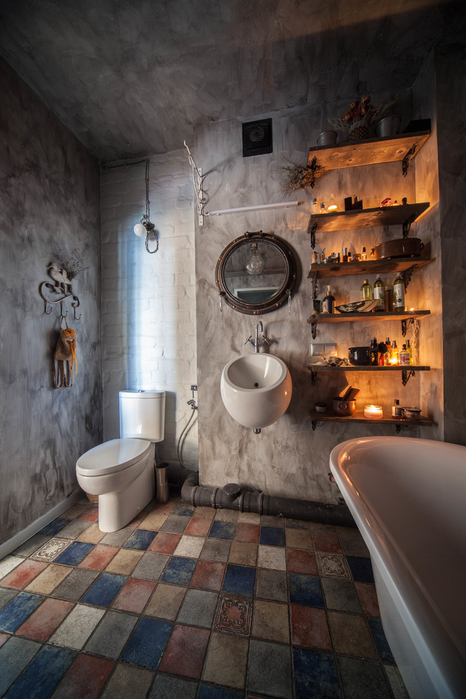 Inspiration för små industriella en-suite badrum, med ett fristående badkar, en toalettstol med separat cisternkåpa, grå väggar, klinkergolv i keramik, ett väggmonterat handfat och flerfärgat golv