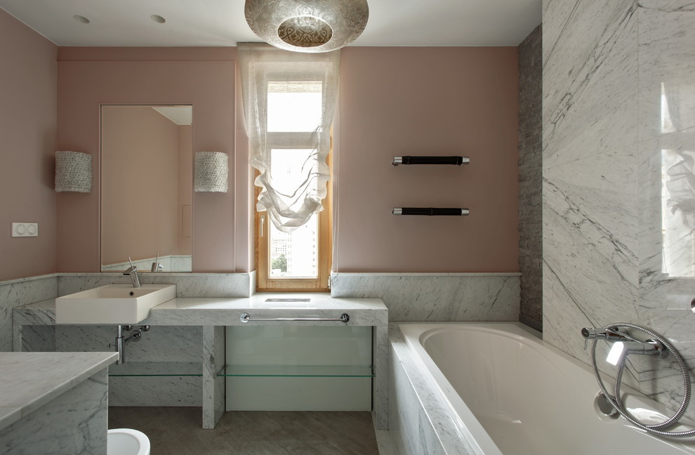 На фото: ванная комната в современном стиле с серой плиткой, плиткой из листового камня, розовыми стенами, накладной раковиной и ванной в нише с