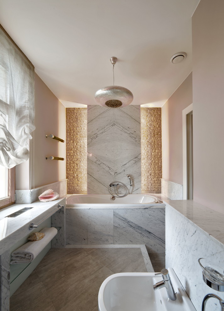 Immagine di una stanza da bagno contemporanea con piastrelle grigie, lastra di pietra, pareti rosa, vasca ad alcova, vasca/doccia e bidè