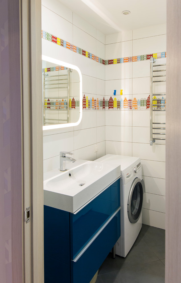 На фото: ванная комната со стиральной машиной в современном стиле с плоскими фасадами, синими фасадами, белой плиткой, полом из сланца, консольной раковиной и серым полом