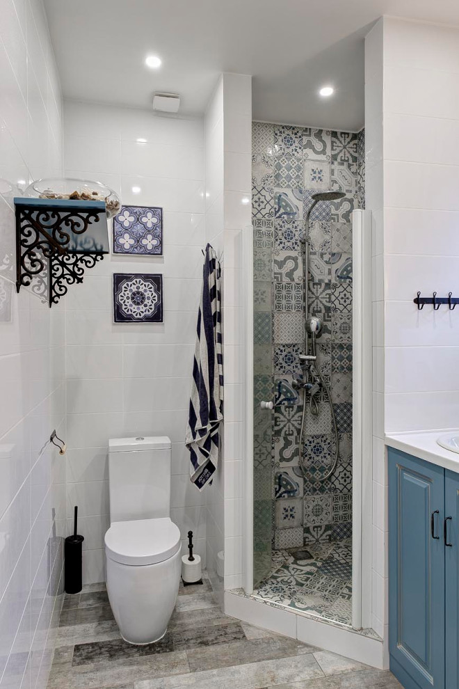 Foto di una stanza da bagno con doccia design con ante con bugna sagomata, ante blu, doccia ad angolo, WC a due pezzi, piastrelle bianche, lavabo da incasso, pavimento grigio, porta doccia a battente e top bianco