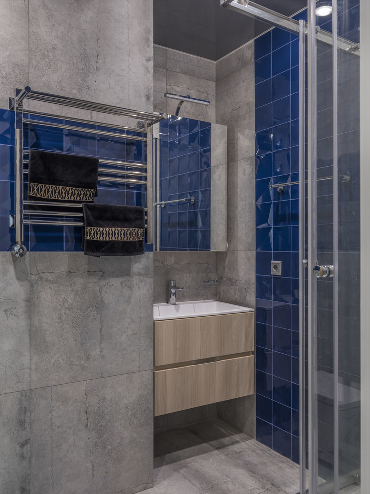 Источник вдохновения для домашнего уюта: ванная комната в современном стиле с плоскими фасадами, светлыми деревянными фасадами, синей плиткой, серой плиткой, душевой кабиной, монолитной раковиной и серым полом