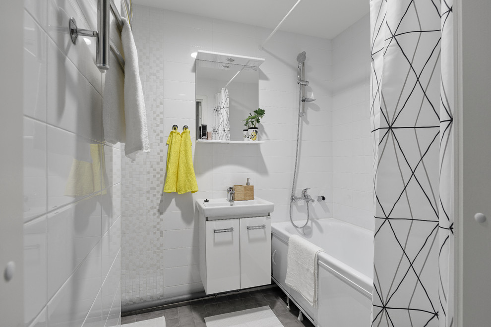 Medium sized scandi ensuite bathroom in Saint Petersburg with flat-panel cabinets, white cabinets, an alcove bath, a shower/bath combination, white tiles, grey floors, a shower curtain, a one-piece toilet, ceramic tiles, white walls, porcelain flooring and a built-in sink.